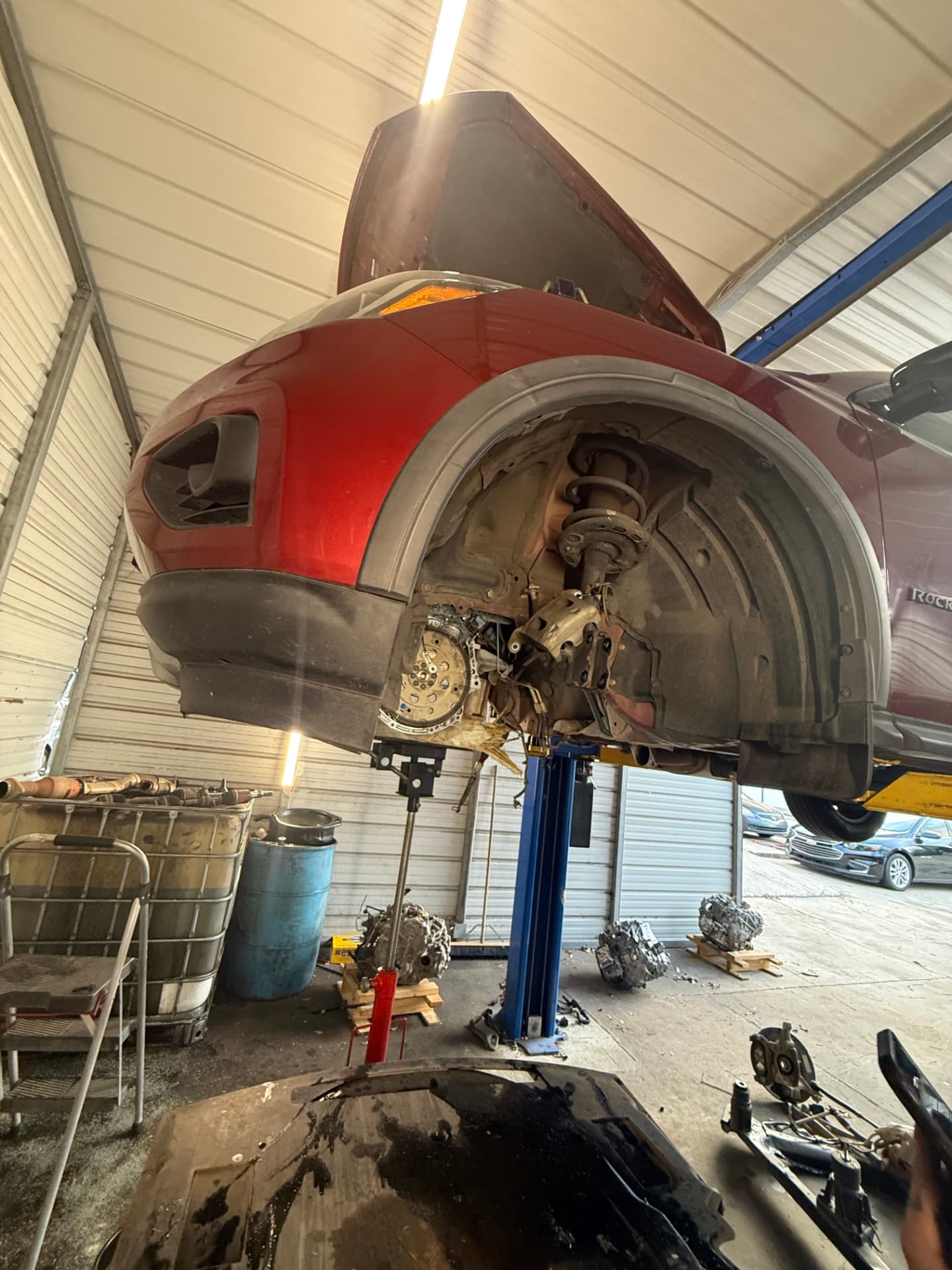 Vehicle on a lift with a transmission jack during a Sam's Auto repair